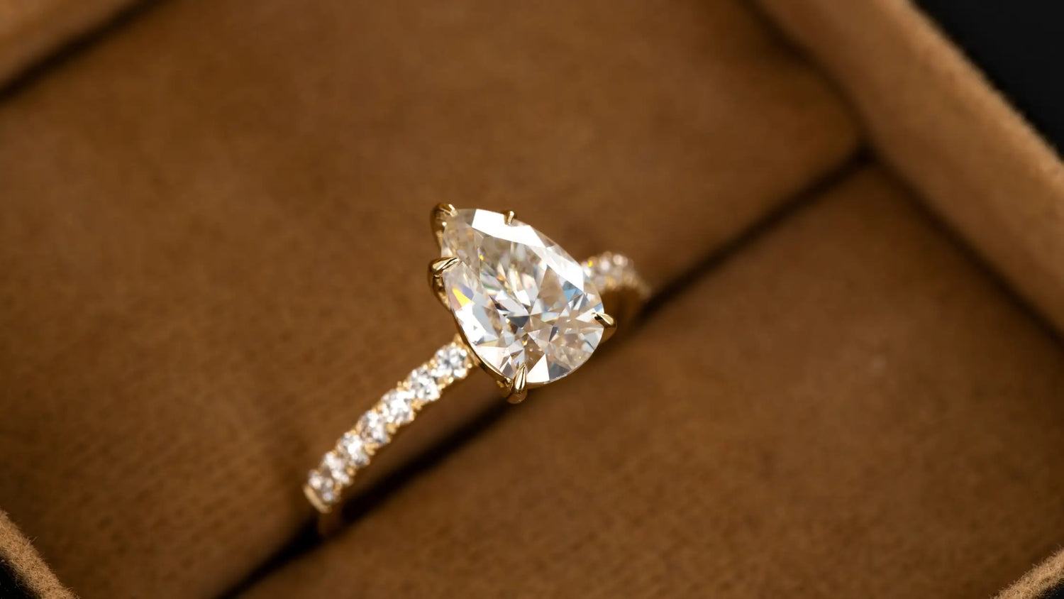 Gold ring with a pear-shaped diamond jewelry on a brown surface